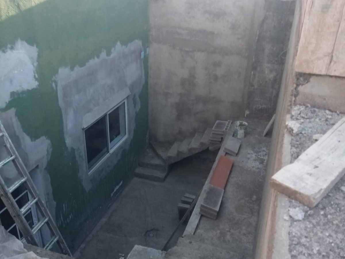 Escalera exterior de hormigón en bruto y pared a medio enfoscar antes de la obra